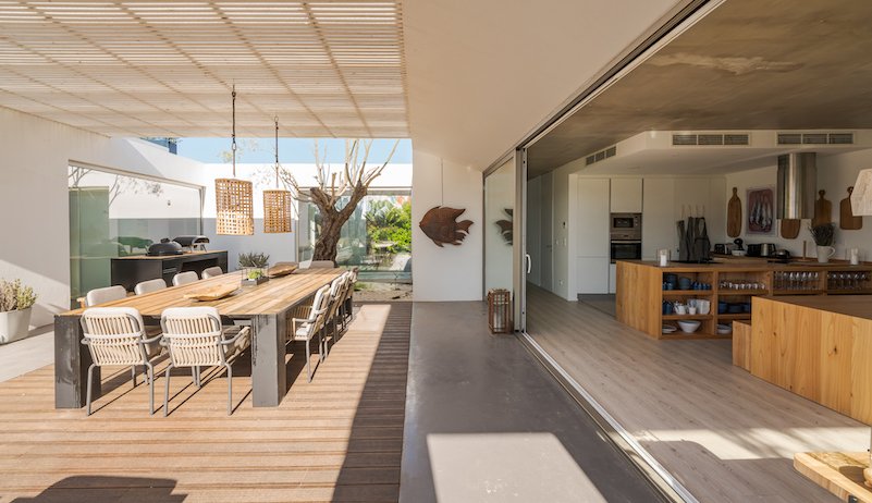 Shadrick Construction An outdoor dining area with beautiful wooden decking, a wooden table and chairs.